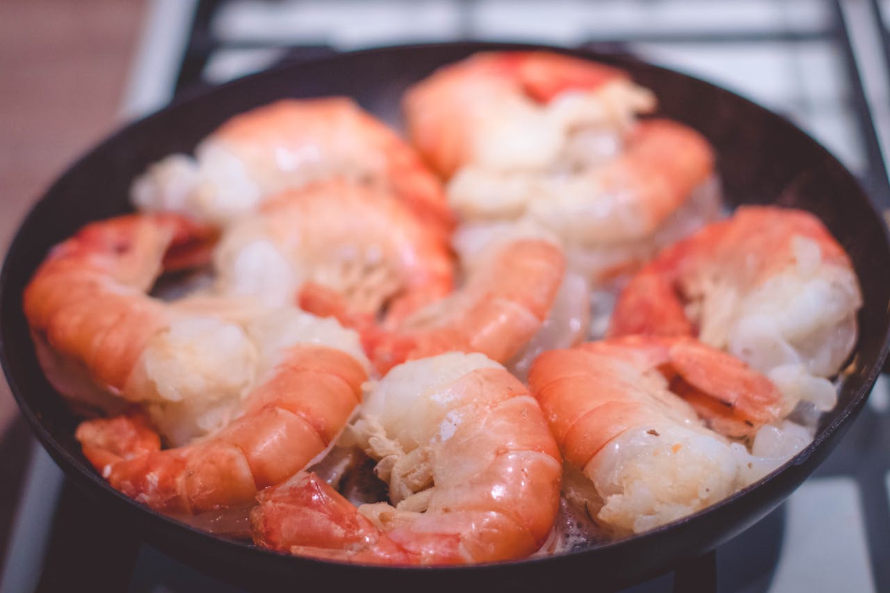 services-05 Delicious close-up of prawns sizzling in a frying pan, perfect for seafood lovers.